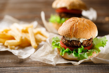 Homemade tasty burger and french fries on wooden table