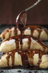 Spoon with chocolate glaze over puffs on plate
