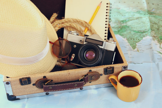 traveling concept. camera, cup of coffee, sunglasses, fedora hat and notebook. vintage filtered. selective focus