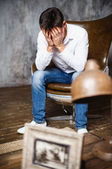 Close-up portrait of gorgeous young man in business style holding hands to head