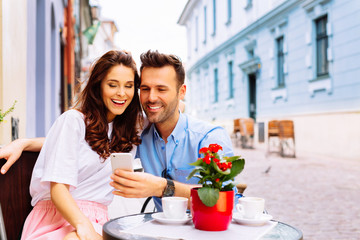 Couple on european vacation sitting in outdoors cafe looking at