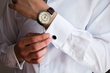 Male hands on a background of a white shirt, sleeve shirt with cufflinks and watches, photographed close-up - obrazy, fototapety, plakaty