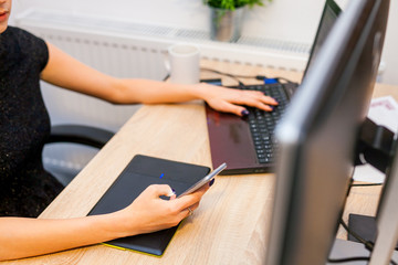 Fototapeta premium Young businesswoman using her touchpad and laptop. She is sittin