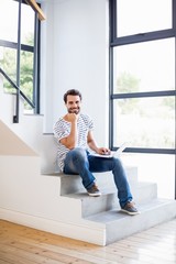 Portrait of happy man sitting on steps using laptop