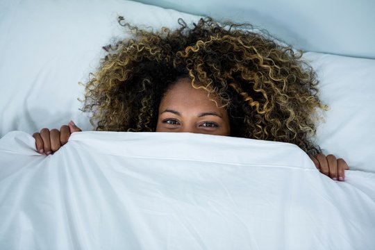Woman Hiding Under Blanket On Bed