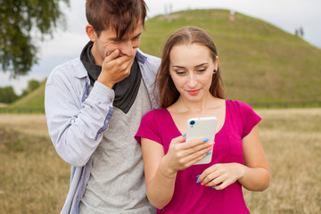 Two friends in a park with mobile phone. Summer time.