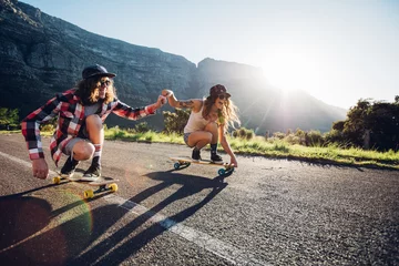 Schilderijen op glas Couple having fun with skateboard on the road © Jacob Lund