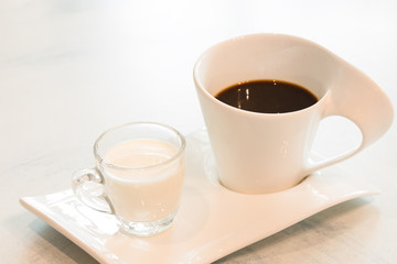 Black coffee and fresh milk on white background