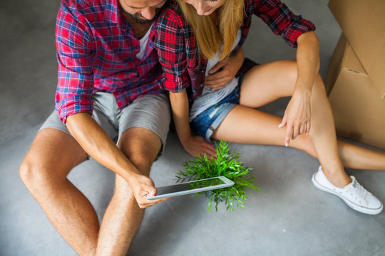 Young Couple Sitting On The Floor With Tablet Pc And Choosing Fu