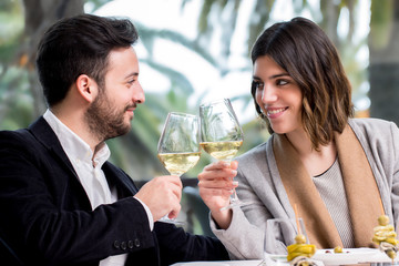 Elegant Couple making toast with white wine in restaurant.