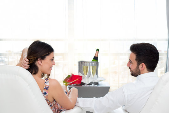 Romantic couple in hotel room celebrating with champagne.