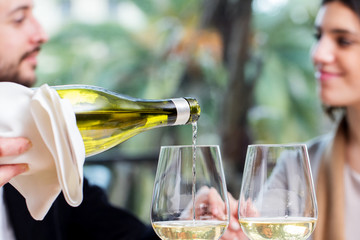 White wine pouring with couple in background.