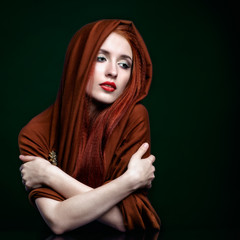Fototapeta premium Young woman with ginger hair and scarf on green background