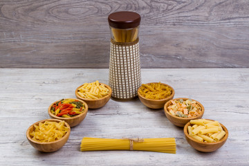 Various combinations of pasta on wooden background, burlap bags, bamboo bowls. diet and nutritional concept.