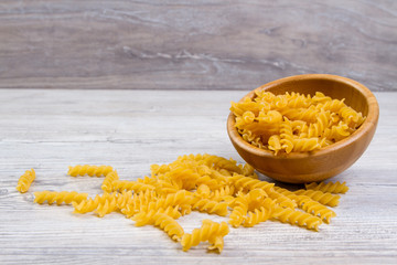 Various combinations of pasta on wooden background, burlap bags, bamboo bowls. diet and nutritional concept.