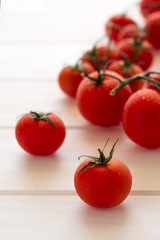 Fresh cherry tomatoes on white wooden background