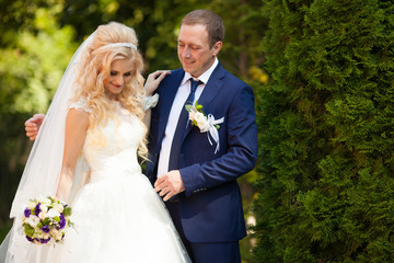 elegant stylish groom with his happy gorgeous blonde bride on th