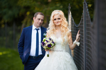 elegant stylish groom with his happy gorgeous blonde bride on th