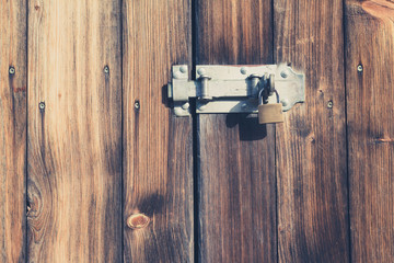 old wooden door with padlock and metal latch