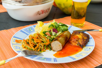 Sausage, salads and potato lying on the plate to eat.