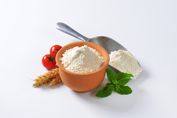 Wheat flour in terracotta dish and metal scoop