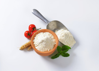 Wheat flour in terracotta dish and metal scoop