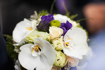 stylish elegant groom with bouquet on the background of luxury c
