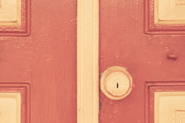 Old door handle on red wall in vintage tone