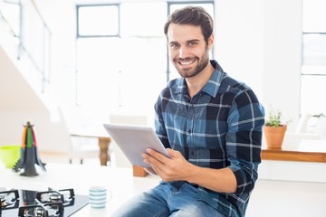 Portrait of happy man using digital tablet in kitchen - Powered by Adobe