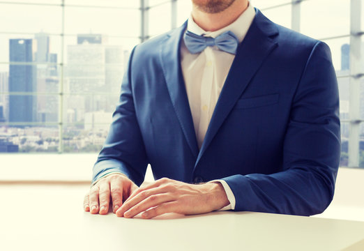 close up of man in suit and bow-tie at table