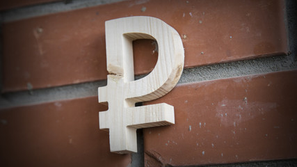 Wooden russian ruble symbol on a brick wall
