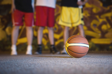 Street basket night scene. Close up of a ball with three players blurry behind