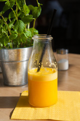 Bottle of Freshly squeezed orange juice sitting on a rustic wooden table.