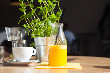 Bottle of Freshly squeezed orange juice sitting on a rustic wooden table.