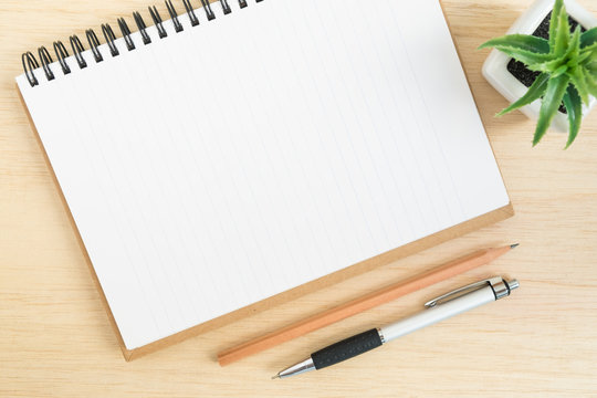 Top View Of Office Desk With Open Spiral Notebook On Wood Table