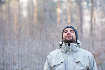 Man breathing deeply in peaceful winter forest on cold day