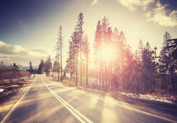 Vintage stylized country road at sunset with Tatra mountains in distance, Poland.