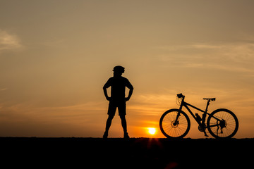 Obraz premium silhouette of man and bicycle on sunset sky