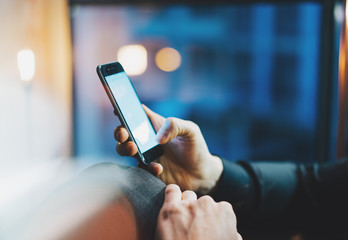 Photo businessman relaxing modern loft office. Man sitting in chair at night. Using contemporary smartphone, blurred background. Horizontal, film, flares effect. 