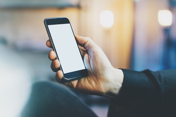 Photo banker relaxing in modern loft office.Man sitting chair night.Using contemporary smartphone,blurred background.Blank screen ready for your business information.Horizontal,film effect. 