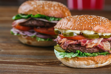 Close up on fresh burger in bun with sesame with lettuce, tomato, beef and bacon. 