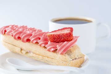 eclair with a strawberry on a background of coffee cups