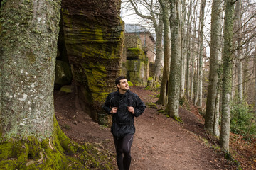Young Man,Student hiking in forest.Man hiker smiling happy portrait looking up enjoying nature on foggy day during a trekking trip. Back of a young man outdoors in nature on a hiker path in forest.