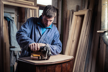 Carpenter restoring furniture with belt sander