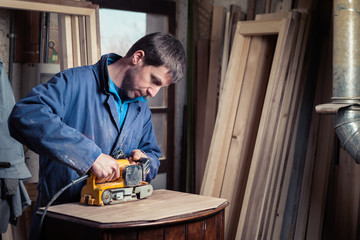 Carpenter restoring furniture with belt sander