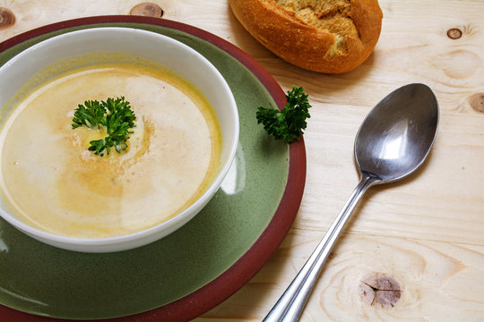 cream soup with parsley garnish in a bowl on a green plate, wooden background