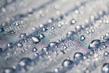 Water droplets on corrugated plastic with refracted light shinning through them at sunrise