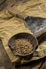 Vecchio mestolo in legno con dentro  grano duro con affianco una spatola per tagliare la pasta della pizza su tovaglietta di carta , sopra tavolo in legno