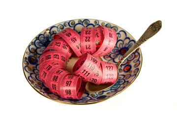 Red spiral measuring tape on the decorated plate with a vintage spoon isolated on white background