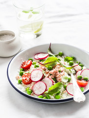 Delicious healthy food - salad with cous cous, fresh vegetables and baked salmon. On a light background